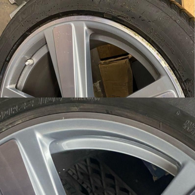 Close-up of two silver car wheels with black tires, one partially overlapping the other.