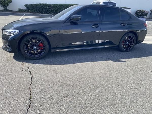 Black sedan parked on a sunny lot, side view with tinted windows and red brake calipers