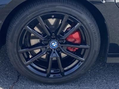 Close-up of a black BMW wheel with red brake caliper on asphalt