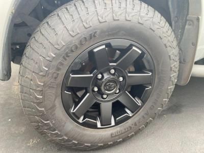 Close-up of a truck tire with a black alloy wheel on a gray pavement.