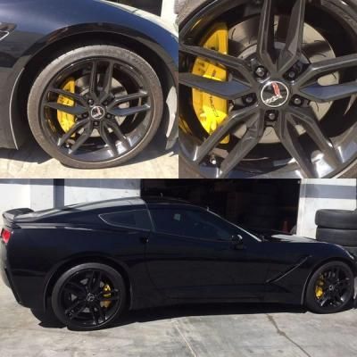 Black sports car with yellow brake calipers, shown in side view and close-up wheel detail.