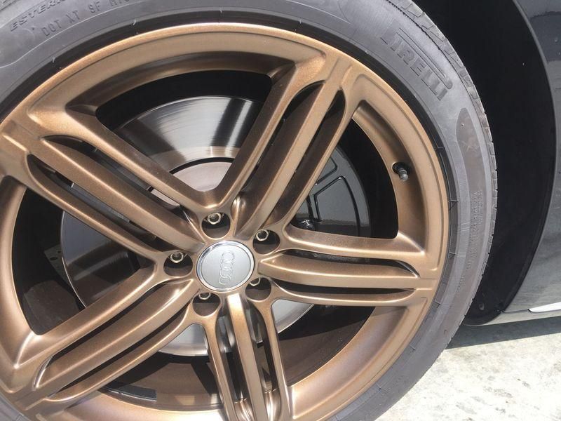 Close-up of a bronze alloy car wheel rim with five spokes and a silver center cap.