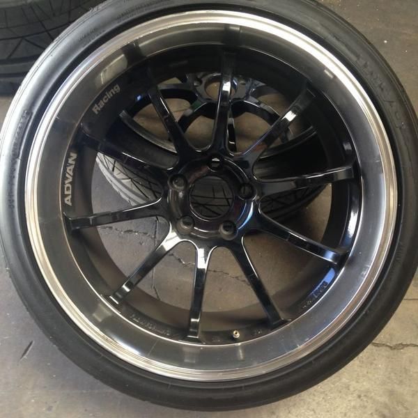 Black multi-spoke alloy wheel with low-profile tire and silver rim, photographed close-up on a floor.