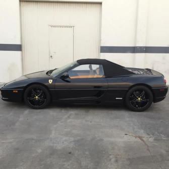 Black Ferrari coupe parked in front of a white industrial garage door