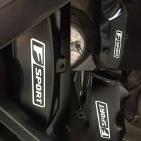 Close-up of a black car interior panel with white “SPORT” logos and a central circular speaker or gauge.