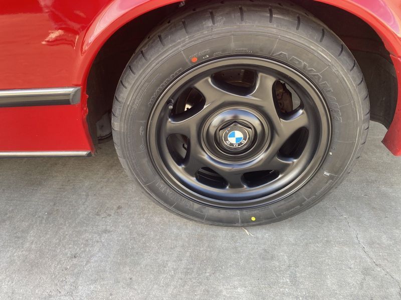 Black BMW wheel on a red car parked on concrete floor