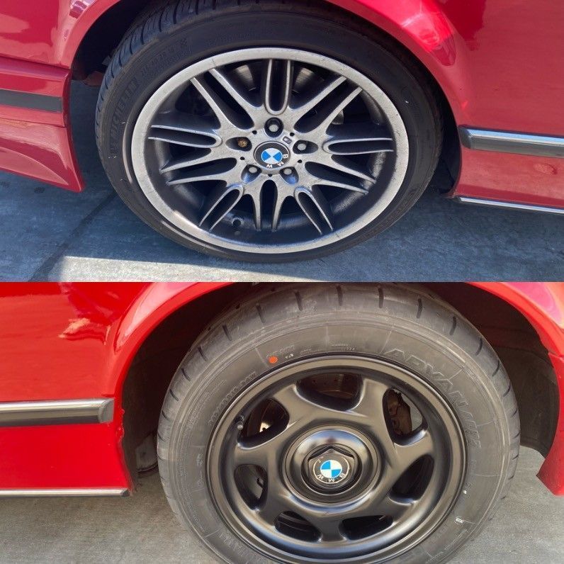 Two car wheels on a red car: top a silver alloy rim, bottom a black steel rim