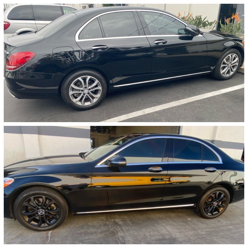 Two black sedans parked side by side, one silver-rimmed and one with black rims.