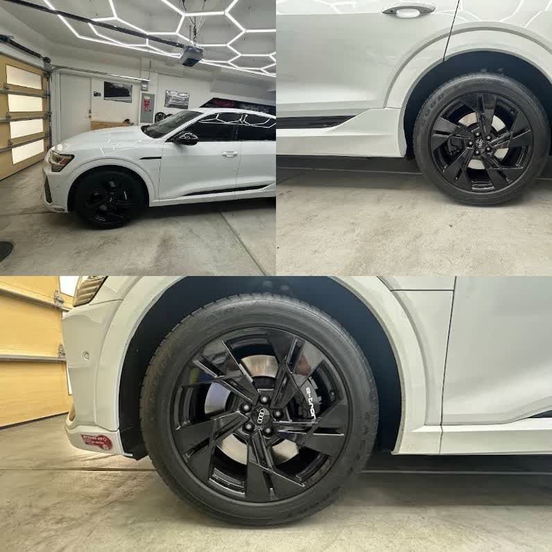White sports car in a garage, shown from the side with black rims and a large rear wheel close-up.