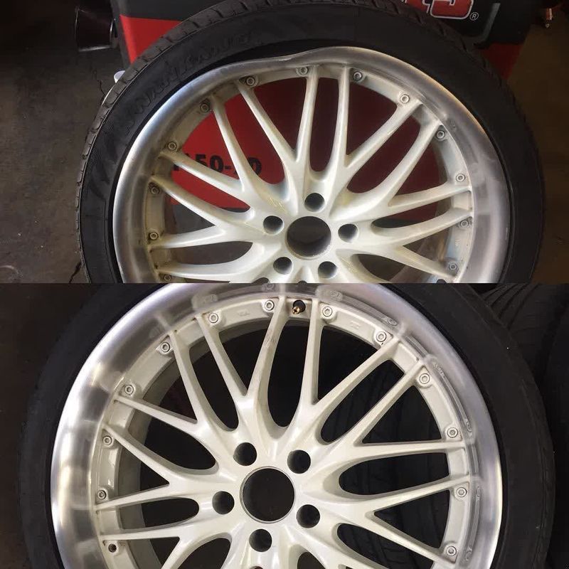 Two silver alloy car wheels with black tires, shown one above the other, with a red vehicle in the background