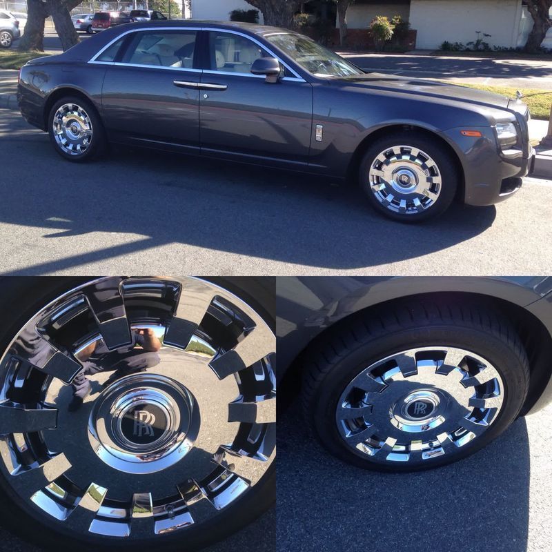 Dark gray luxury sedan with chrome custom wheels, shown in profile and close-up on a sunny street.