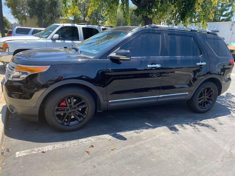 Black SUV parked outdoors in a lot, side view, with tinted windows and red brake calipers