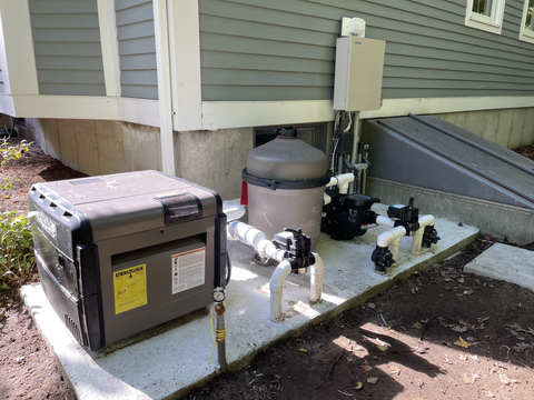 A swimming pool heater and filter are sitting on the side of a house.