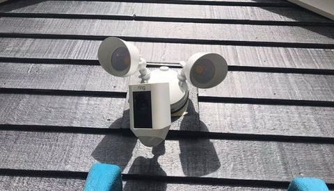 A ring security camera is sitting on top of a roof.