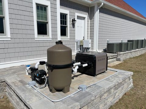 A swimming pool filter and heater are sitting outside of a house.
