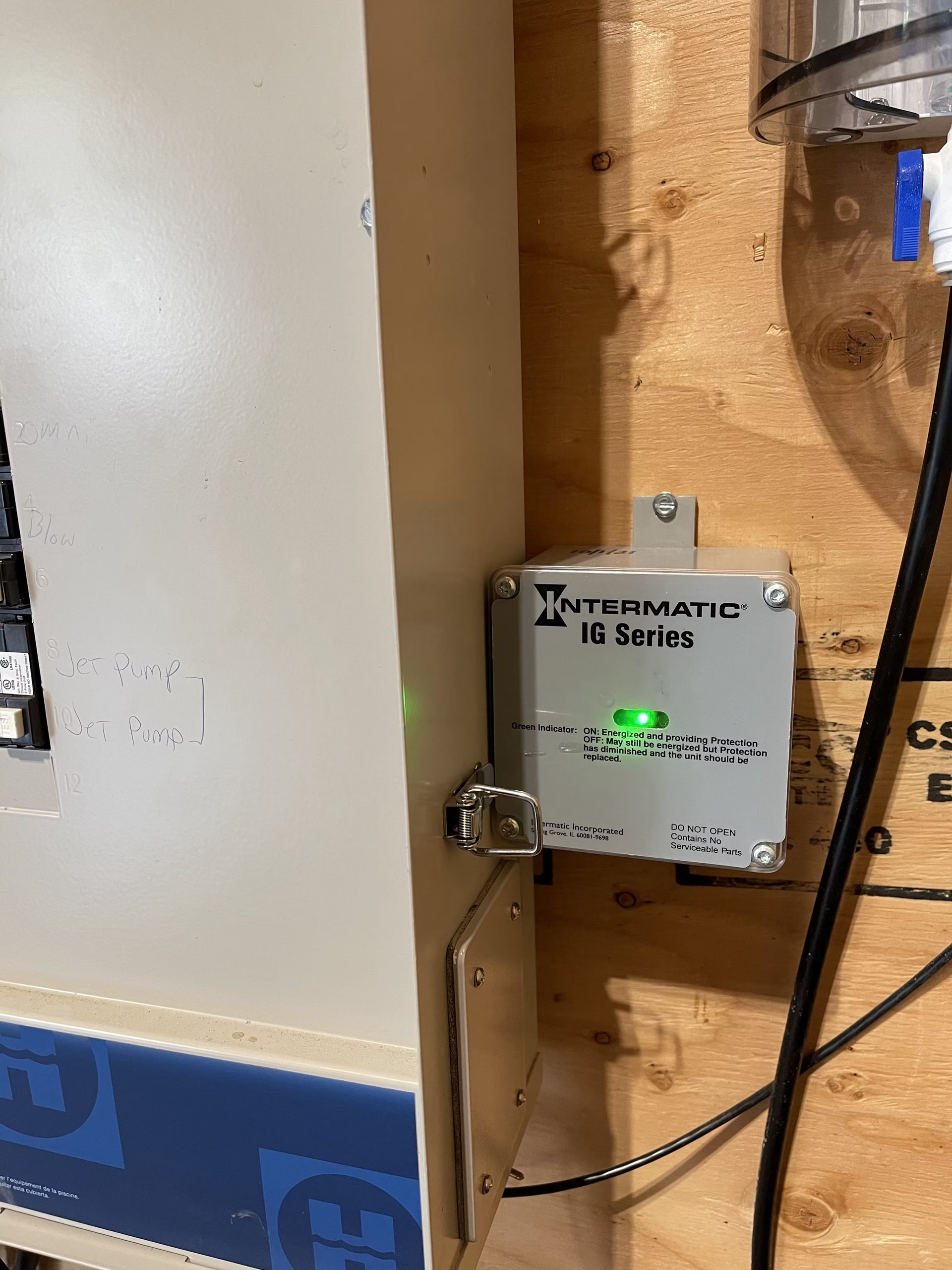 A white box with a green light on it is attached to a wooden wall.