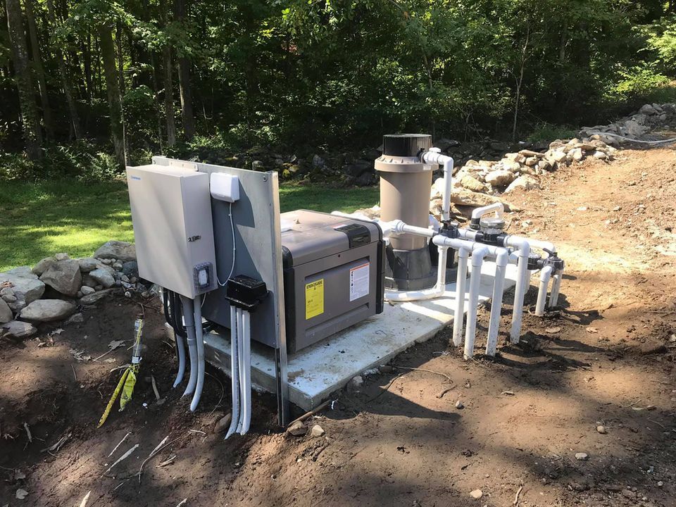 A swimming pool pump is sitting on top of a concrete platform in the dirt.
