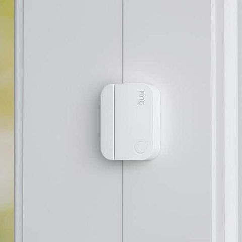 A white door sensor is attached to a white door.