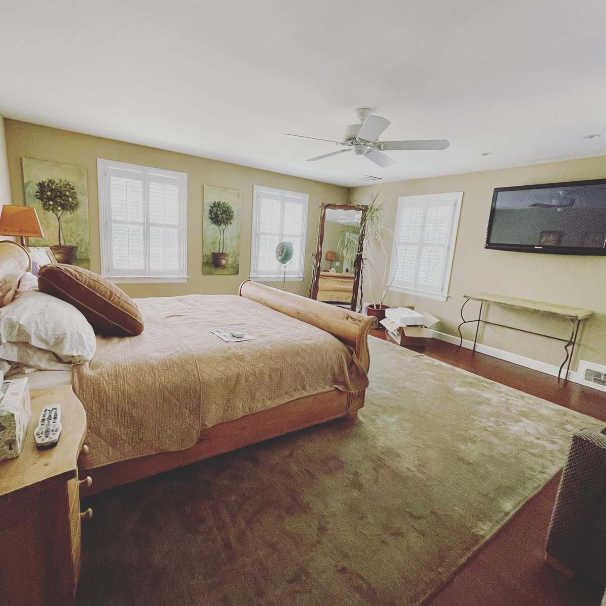 A bedroom with a large bed and a flat screen tv on the wall.