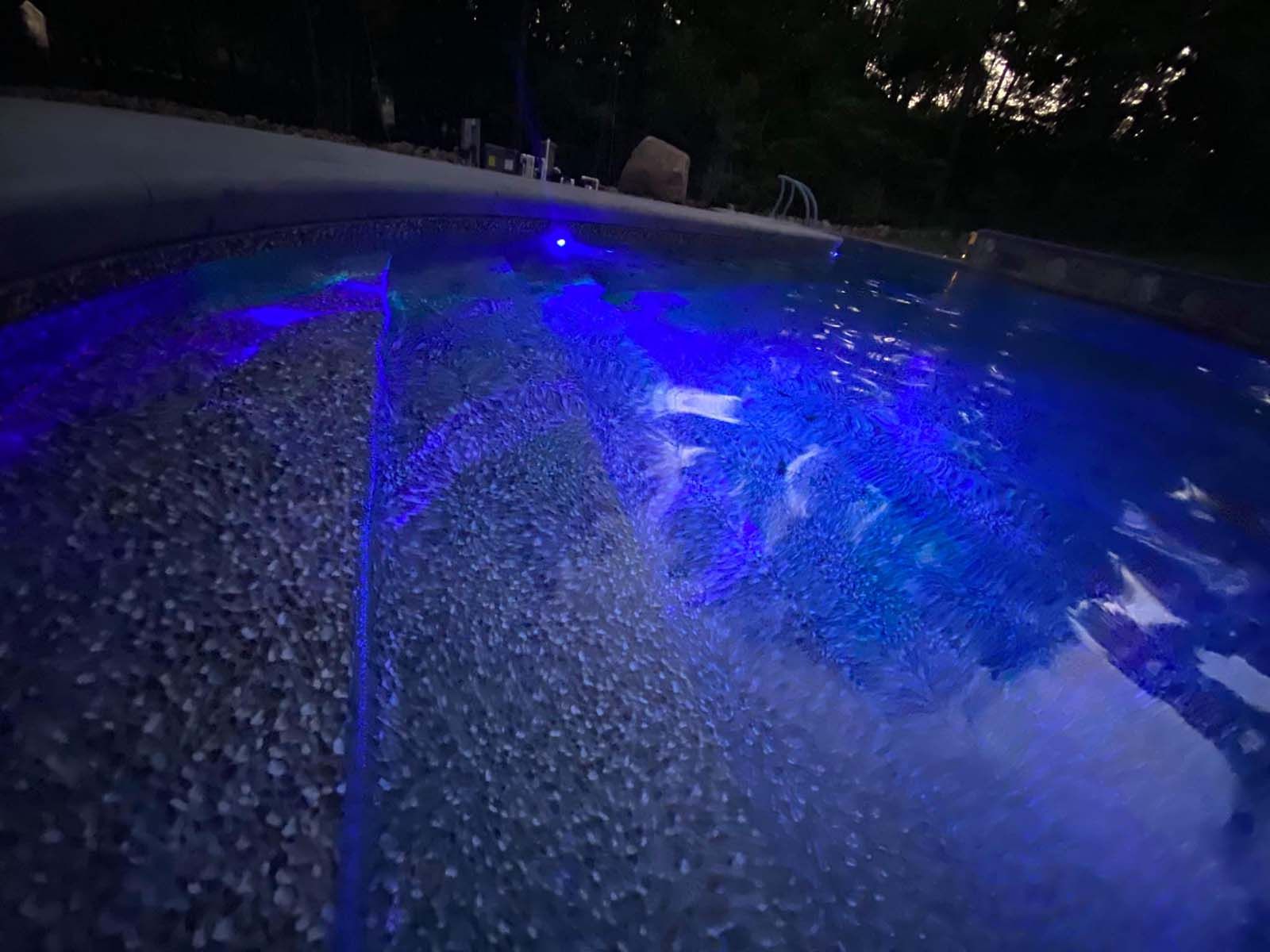 A swimming pool with blue lights on it at night.