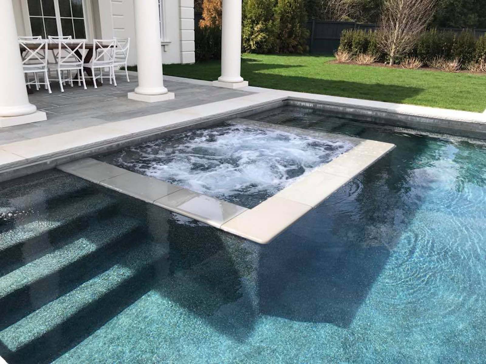 A large swimming pool with a hot tub in the middle of it.