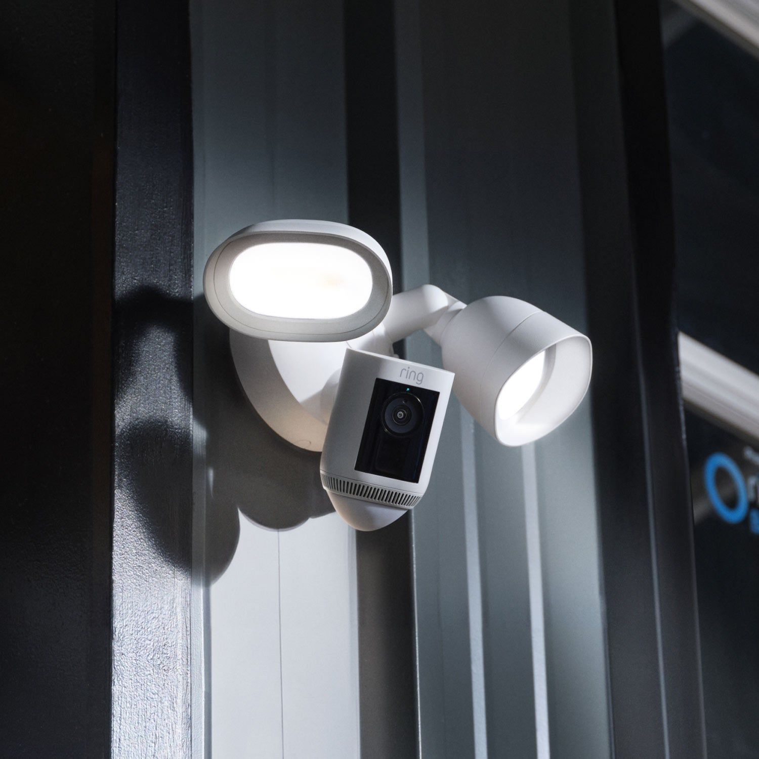 A security camera is mounted on a wall next to a light.