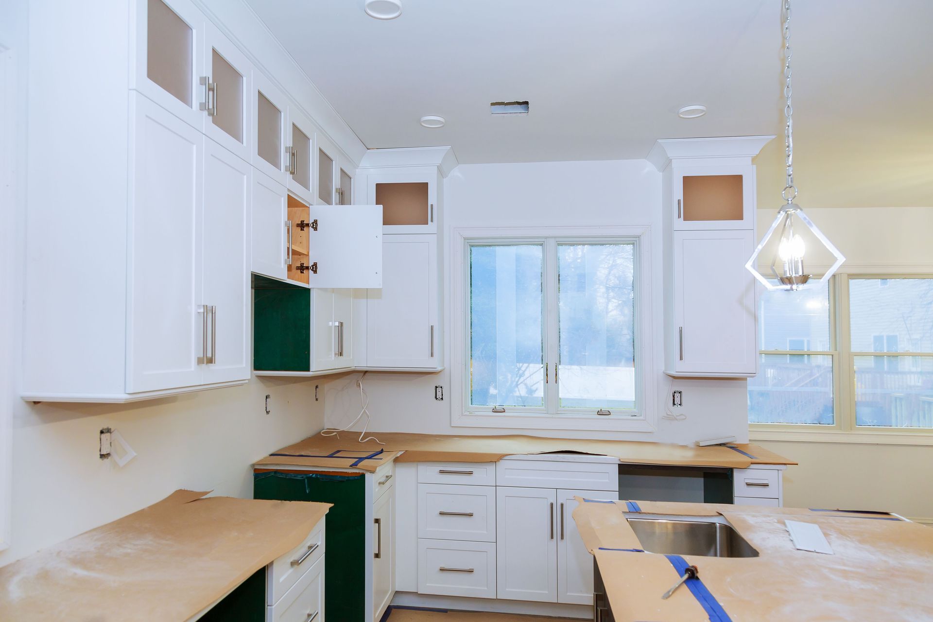 Bright white kitchen with unfinished cabinets, wood countertops, and a large window.
