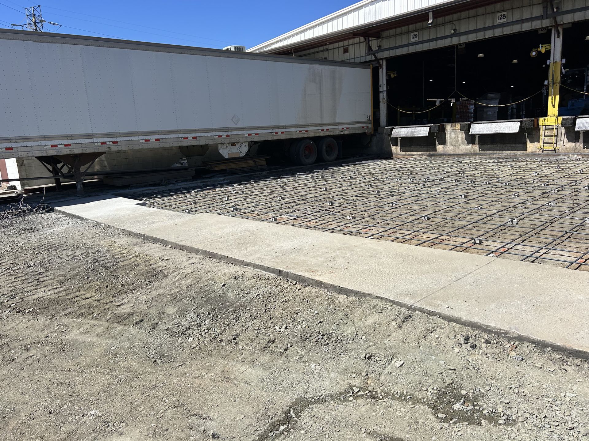 A white semi truck is parked in front of a warehouse.