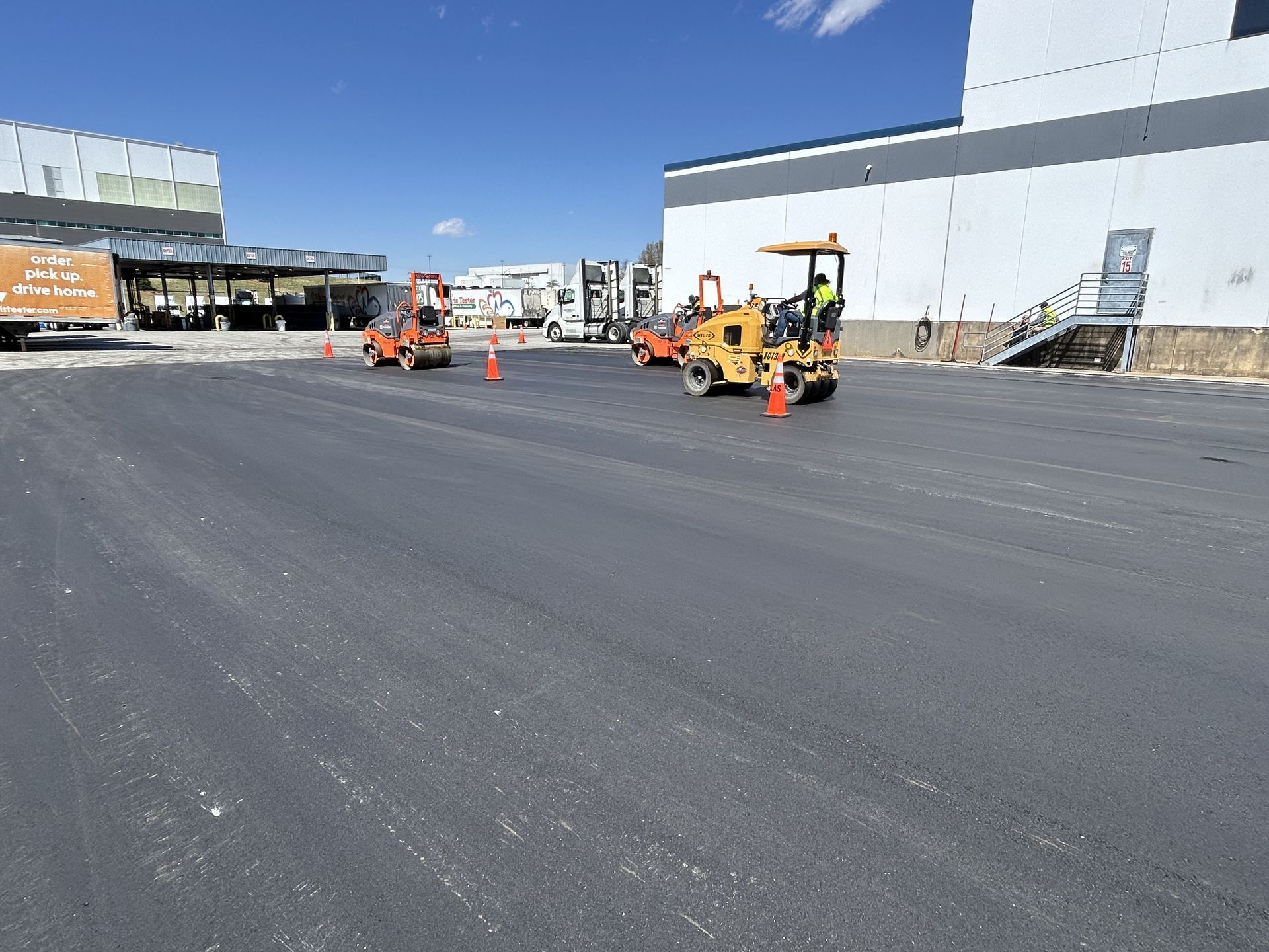 A group of construction vehicles are working on a road in front of a building.