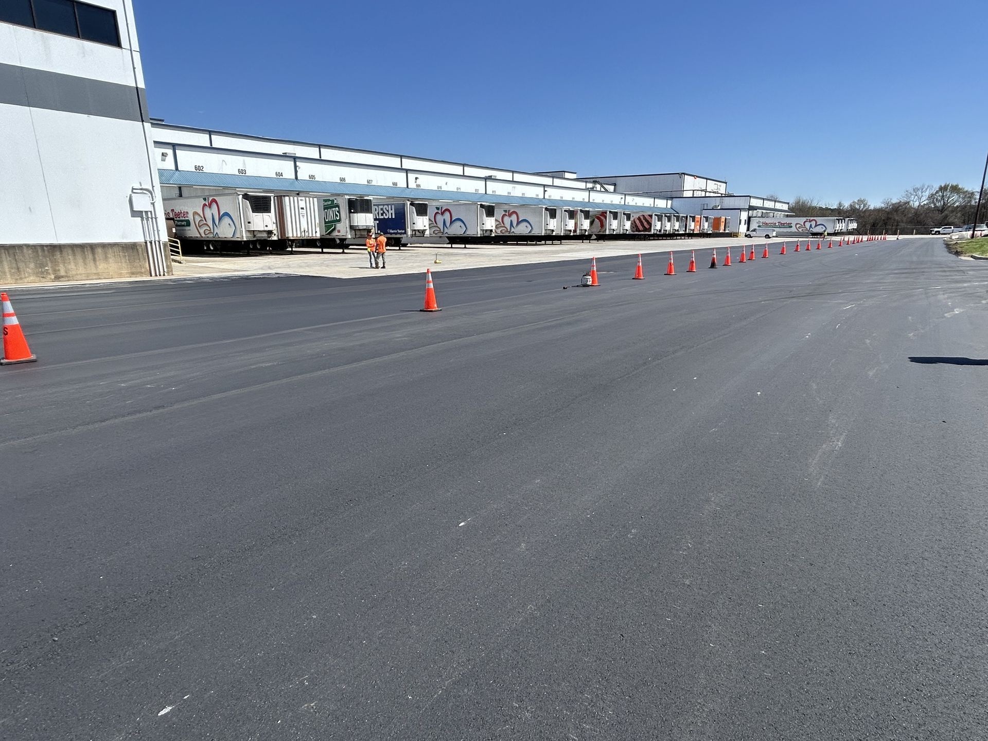 A row of orange cones are lined up on the side of a road in front of a building.