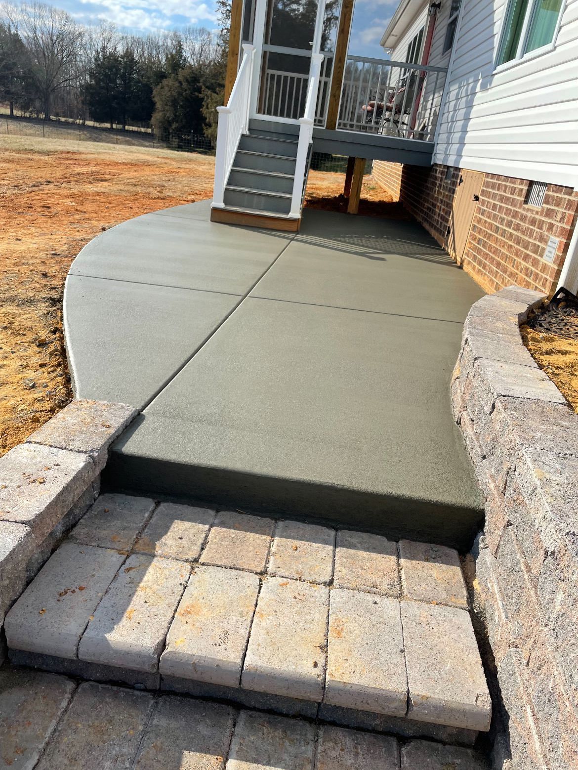 a concrete walkway leading to a house with stairs and a deck
