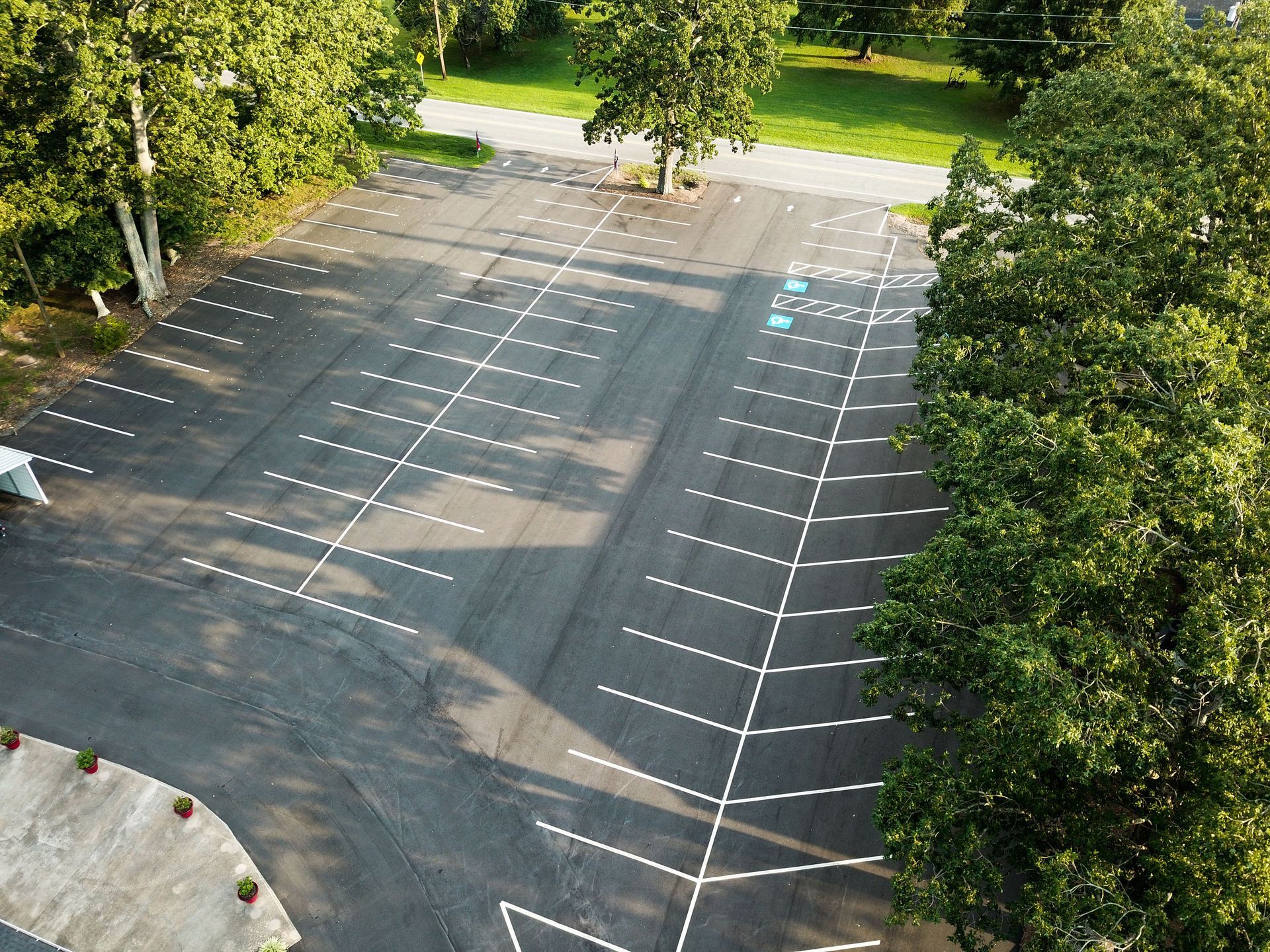 an aerial view of a parking lot with trees in the background