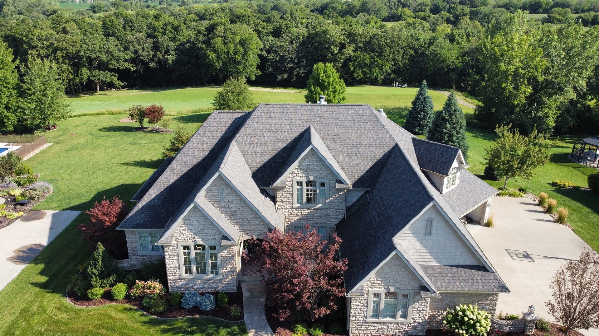 An aerial view of a large house surrounded by trees and grass.