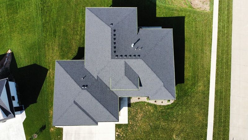 An aerial view of a house with a gray roof and a driveway.