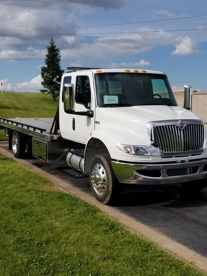 White International tow truck parked on asphalt next to grass.