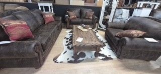 Living room with dark brown leather sofas, wooden coffee table, and patterned rug