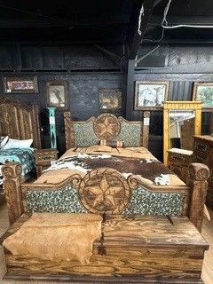 Ornate wooden bed with patterned bedding in a dark, rustic bedroom interior