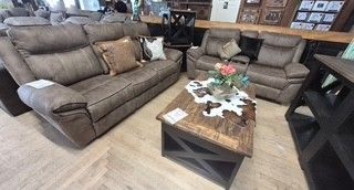 Furniture showroom with brown sectional sofas and a rustic coffee table on a light wood floor