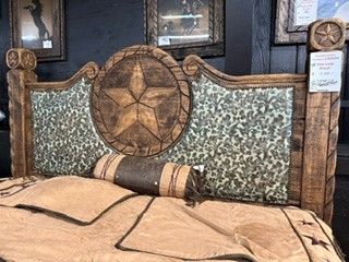 Rustic carved wooden bed with star medallion headboard and beige bedding in a bedroom