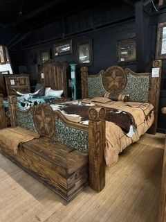 Rustic wooden bed with tan bedding in a dark, antique-style bedroom