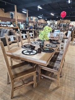 Wooden dining table with six chairs and black star placemats in a furniture showroom