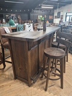Wooden bar table and stools in a rustic restaurant interior, with shelves and decor in the background