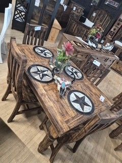 Rustic wood dining table set with star-pattern placemats and a pink flower centerpiece
