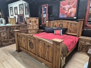 Wooden bedroom set with red bedding, dresser, and wall art in a rustic dark-wood room