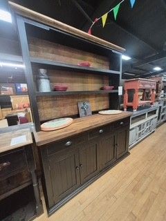 Dark wood hutch with shelves and cabinets displayed in a furniture store aisle