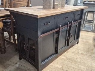 Dark gray kitchen island with wood top and storage shelves in a rustic room