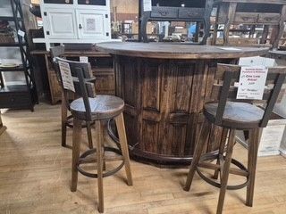 Rustic wooden bar table with two stools in a furniture showroom.