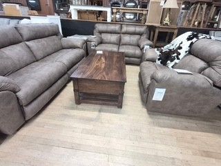 Furniture showroom with gray sectional sofas, a matching chair, and a dark wood coffee table on a light rug.