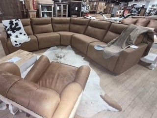 Brown sectional sofa in a furniture store, with matching chair and rug samples on display.