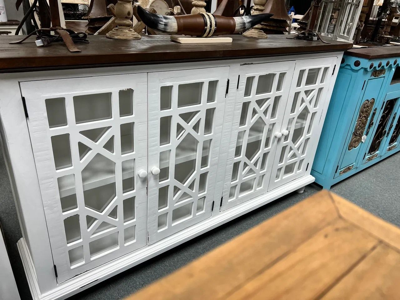 White cabinet with geometric door designs, wood top, and a blue cabinet to the right.